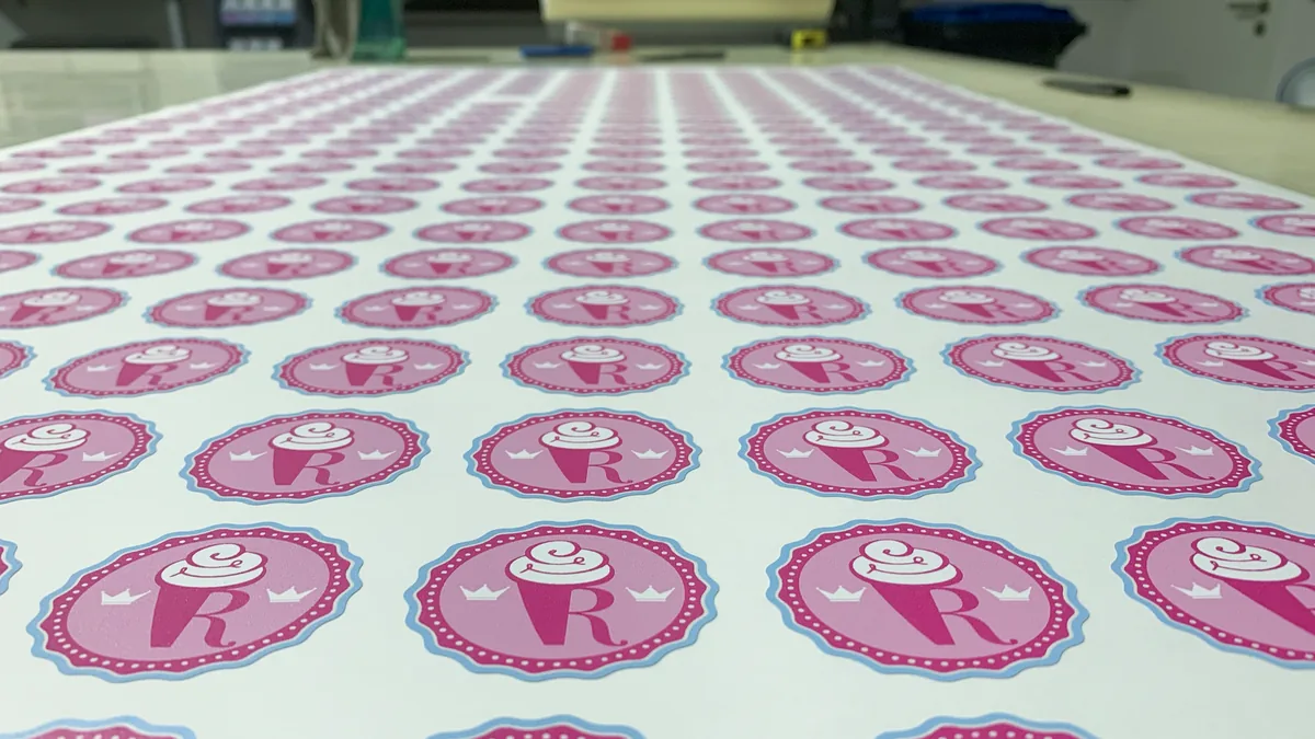 Bogen mit runden Aufklebern im Konturschnitt, Logo in Rosa und Hellblau