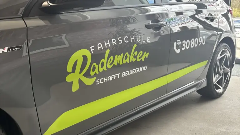 Dunkelgrauer PKW mit Schriftzug auf der Fahrertür und grünem Farbverlauf am Schweller