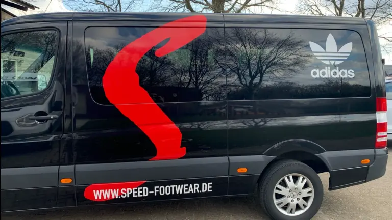 Schwarzer Transporter mit roter Teilfolierung über die gesamte Seitenwand