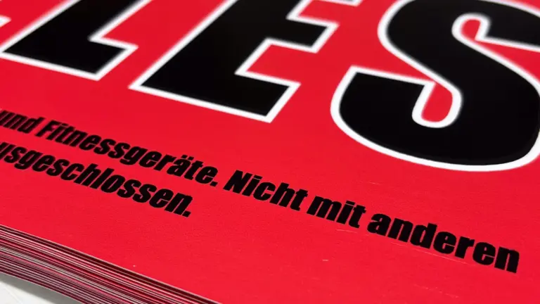 Stapel frisch gedruckter roter Plakate mit großer schwarzer Schrift, Nahaufnahme der Kante