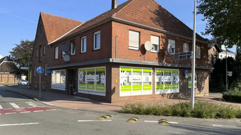 Eckgebäude aus rotem Klinker mit beschrifteten Schaufenstern an beiden Fassadenseiten