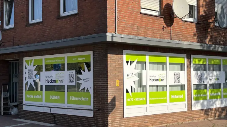 Schaufenster mit farbiger Folienbeschriftung, Logo, Stichworten und QR-Code auf der Scheibe