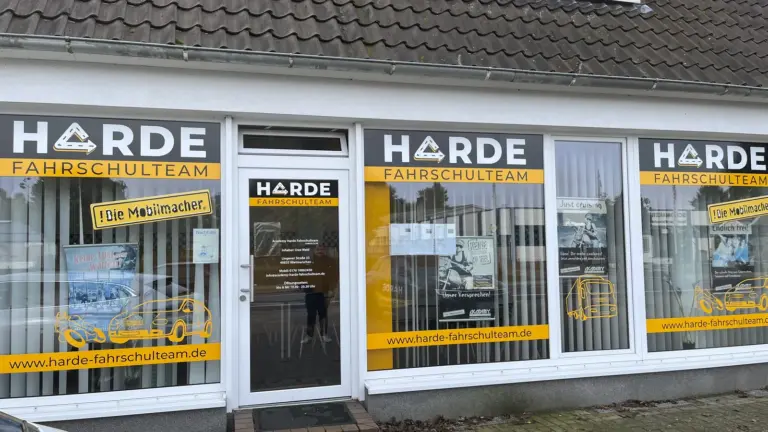 Ladenfront mit gelb-weißer Folienbeschriftung über alle Fenster und die Eingangstür