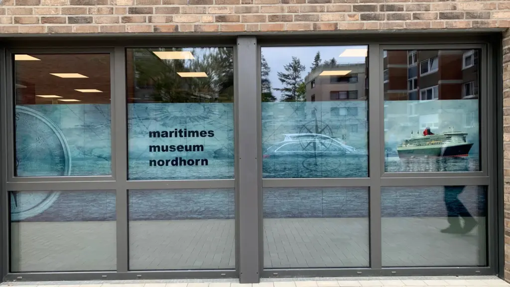 Ladenfront mit bedruckter Fensterfolie: Seekarte, Kompass und Schiffsmotive mit Schriftzug