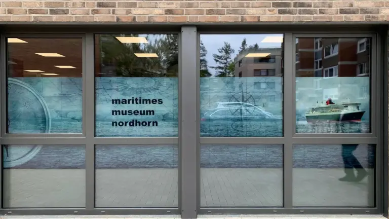 Ladenfront mit bedruckter Fensterfolie: Seekarte, Kompass und Schiffsmotive mit Schriftzug