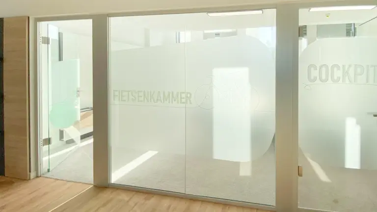 Glaswand mit Sichtschutzfolie, Raumname und Fahrrad als Liniengrafik